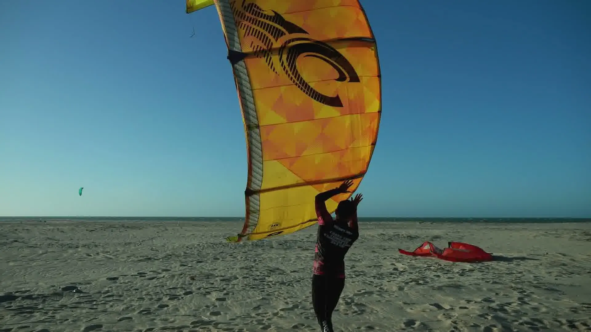 Kitesurfista preparando a pipa na areia branca