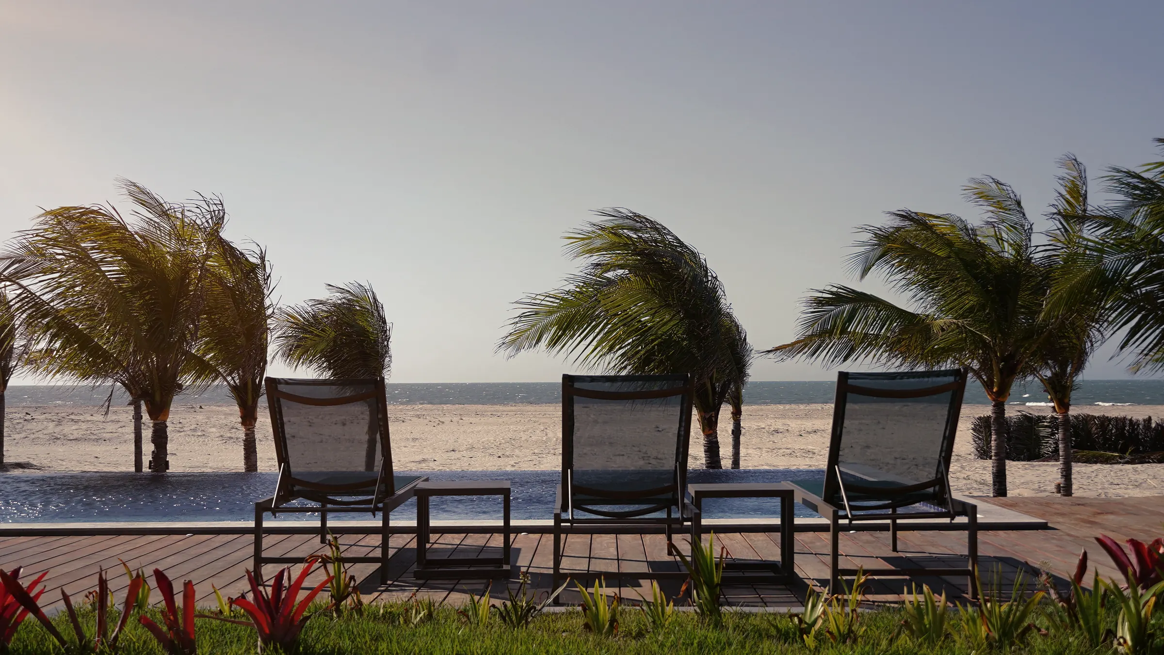 Espreguiçadeiras junto à piscina, de frente para o mar