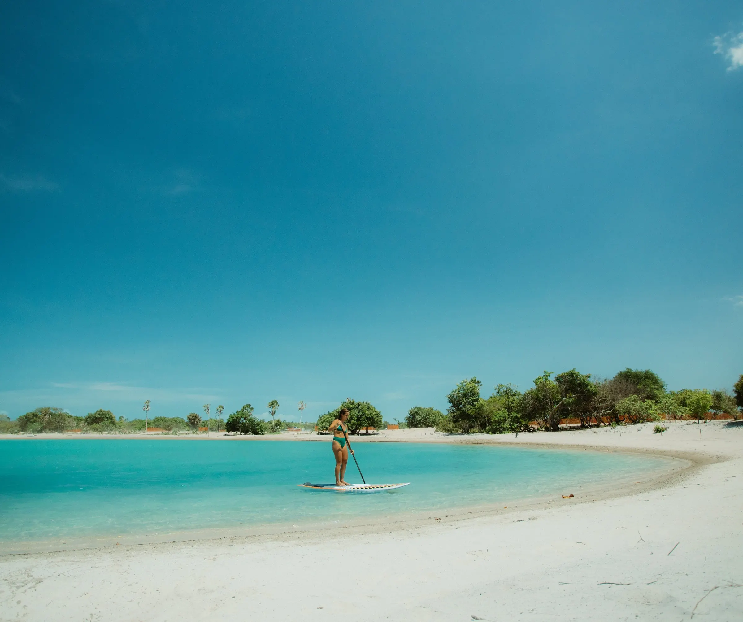Lagoa turquesa com um praticante de stand up paddle ao longe